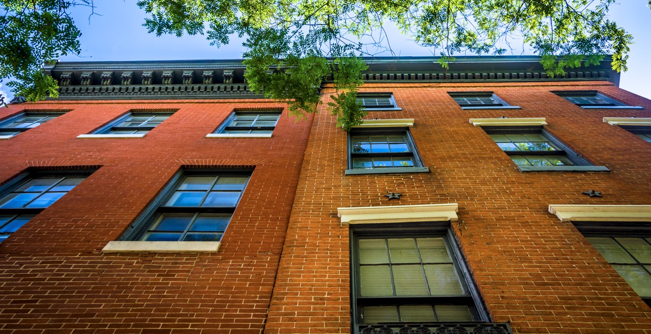 Image looking up at a red brick row home in Washington, DC
